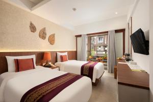 a hotel room with two beds and a television at Nadi Hotel Legian in Legian