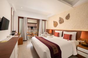 a hotel room with a large white bed and a television at Nadi Hotel Legian in Legian