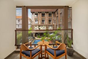 a balcony with a table and chairs and a large window at Nadi Hotel Legian in Legian