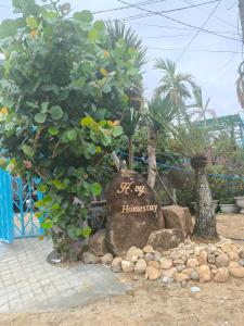 a sign on a rock in front of some trees at H Vy Homestay in Phương Phi