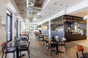 a restaurant with tables and chairs and a bar at Mantra MacArthur Hotel in Canberra