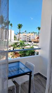 a table and chairs on a balcony with palm trees at Coral Beach Hotel Punta Cana in Punta Cana
