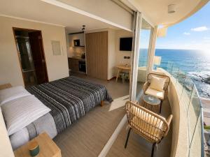 a bedroom with a bed and a balcony with the ocean at Estudio peninsula Cavancha in Iquique