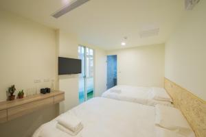 a bedroom with two beds and a flat screen tv at Hostel Jiizu in Taipei