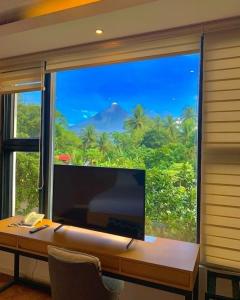 a desk with a large window with a view of a mountain at Wyndale Hotel in Camalig