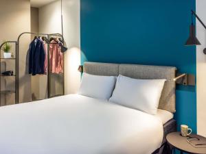 a bedroom with a white bed and a blue wall at ibis Manchester Centre Princess Street in Manchester