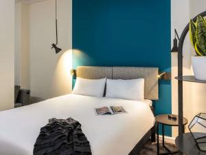 a bedroom with a white bed with a blue wall at ibis Manchester Centre Princess Street in Manchester +73 photos