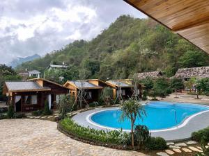 a resort with a swimming pool in front of a mountain at Fullhouse Mộc Châu in Mộc Châu