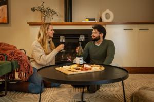 a man and woman sitting around a table with a glass of wine at Hermitage Lodge in Pokolbin