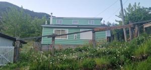 a green house with a fence in front of it at Cabaña el Sauco in Puerto Guadal