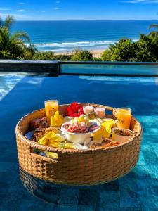 a basket filled with food and drinks on a swimming pool at Pousada Rosa Norte in Praia do Rosa