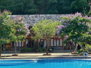 a house with trees in front of a swimming pool at Fullhouse Mộc Châu in Mộc Châu