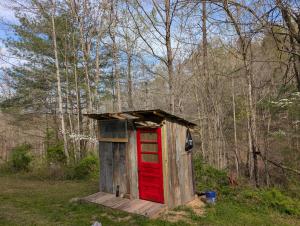 a out house with a red door in the woods at Goldenrod Gap in Wellington
