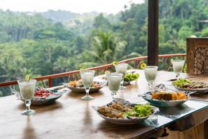 a table with plates of food and glasses of water at River Song Ubud, Bali in Ubud
