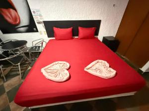 a red bed with a red blanket and shoes on it at Hotel Boppard in Mexico City
