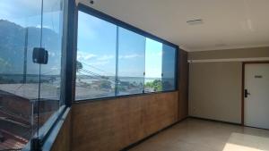 an empty room with a large window in a building at Riviera Sanary Praia, Conforto e Tranquilidade in Serra