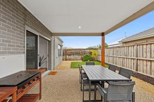 an outdoor patio with a wooden table and chairs at Point Retreat in Point Lonsdale