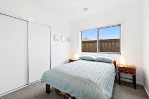 a white bedroom with a bed and a window at Point Retreat in Point Lonsdale