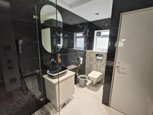 a bathroom with a sink and a toilet and a mirror at Hotel Melody Boutique Thane in Thane