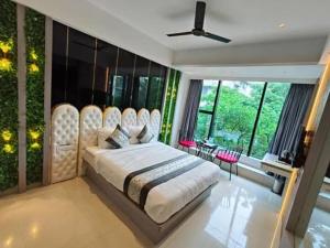 a bedroom with a large bed with large windows at Hotel Melody Boutique Thane in Thane