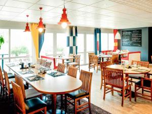 a dining room with tables and chairs and windows at ibis Brest Kergaradec in Brest
