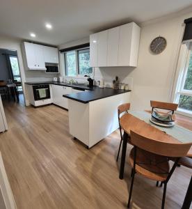a kitchen with white cabinets and a table and chairs at Grey Gum Getaway Tecoma in Belgrave +19 photos