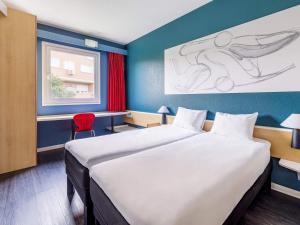 a room with a large bed and a red chair at Ibis Madrid Getafe in Getafe