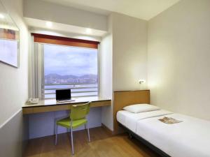 a bedroom with a bed and a desk with a laptop at ibis Hong Kong North Point in Hong Kong +90 photos