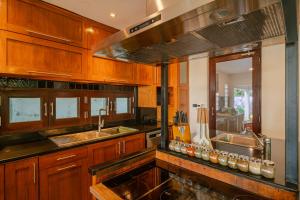 a kitchen with wooden cabinets and a sink at Kiri Anda Villa Phuket in Rawai Beach