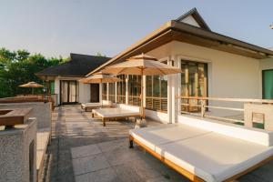 a patio with benches and umbrellas on a building at Kiri Anda Villa Phuket in Rawai Beach