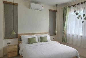 a bedroom with a large white bed with green pillows at Neramit House in Ko Phangan