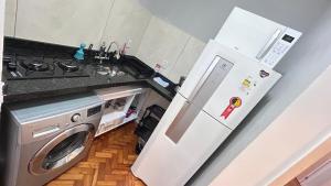 a kitchen with a refrigerator and a washing machine at Studio Copacabana Exclusivo, Na Rua Silva Castro, 4 min da Praia e Metrô, Ganhe 1 ESPUMANTE de boas vindas nas reservas acima de 3 dias, para brindar essa experiência icônica, com Ar e Wi-Fi in Rio de Janeiro