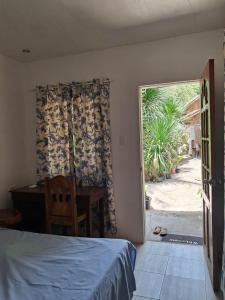 a bedroom with a bed and a desk and a window at Bebot's Breakfast #01 in Daanbantayan