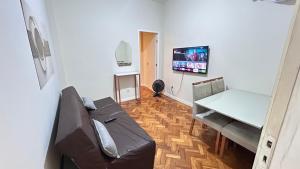 a living room with a couch and a table and a tv at Studio Copacabana Exclusivo, Na Rua Silva Castro, 4 min da Praia e Metrô, Ganhe 1 ESPUMANTE de boas vindas nas reservas acima de 3 dias, para brindar essa experiência icônica, com Ar e Wi-Fi in Rio de Janeiro