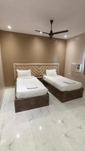 a bedroom with two beds and a ceiling fan at Hotel Sukhdham in Allahābād +30 photos