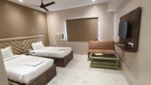 a hotel room with two beds and a tv at Hotel Sukhdham in Allahābād