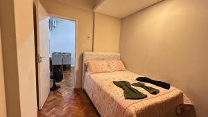 a bedroom with a bed with two green shoes on it at Studio Copacabana Exclusivo, Na Rua Silva Castro, 4 min da Praia e Metrô, Ganhe 1 ESPUMANTE de boas vindas nas reservas acima de 3 dias, para brindar essa experiência icônica, com Ar e Wi-Fi in Rio de Janeiro +54 photos