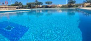 a large pool of blue water with trees in the background at Calpe vistas al mar in Ifach