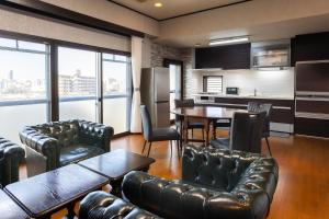 a living room with leather furniture and a kitchen at La Pace Awaji in Osaka