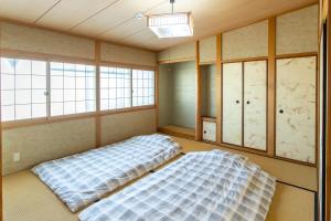 two beds in a room with windows at La Pace Awaji in Osaka