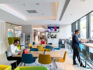 two men standing in a restaurant with tables and chairs at Novotel Monte-Carlo in Monte Carlo