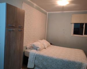a small bedroom with a bed and a cabinet at Casa hospedaje en el campo in Temuco