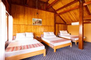 two beds in a room with wooden walls at Fullhouse Mộc Châu in Mộc Châu