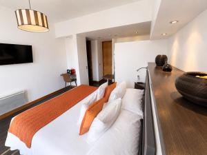 a bedroom with a bed with white sheets and orange pillows at BHB Hotel Boutique in Santiago