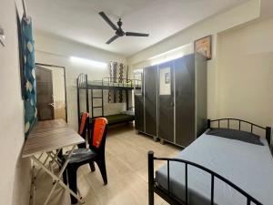 a bedroom with a bed and a table and a desk at Alpine Hostel Services in Pune