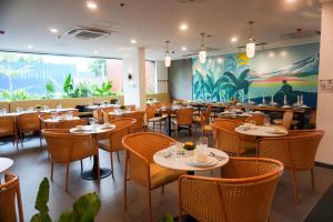 a restaurant with tables and chairs and a large mural at Wyndale Hotel in Camalig