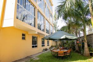 a table and chairs with an umbrella in front of a building at ACARA HAVEN Kisumu in Kisumu