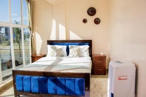 a bedroom with a blue bed and a window at ACARA HAVEN Kisumu in Kisumu