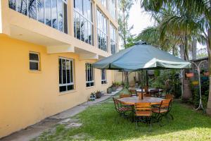 a table and chairs with an umbrella in front of a building at ACARA HAVEN Kisumu in Kisumu +14 photos