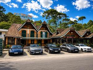 a group of cars parked in front of a house at Pousada do Sino - 2 min do Capivari in Campos do Jordão